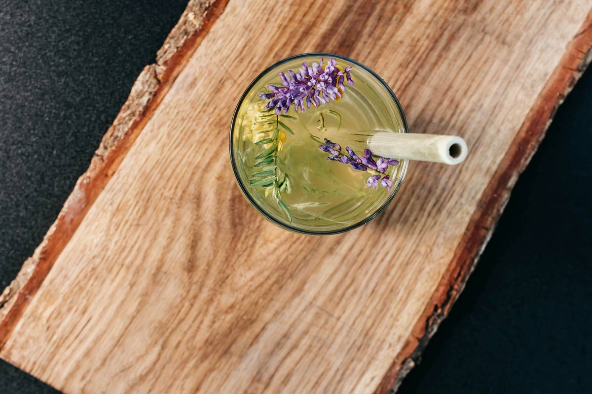 supplements to add to smoothies: glass blender with vibrant green smoothie, visible scoops of organic powder beside it and small bowls of chia seeds, turmeric, and hemp hearts